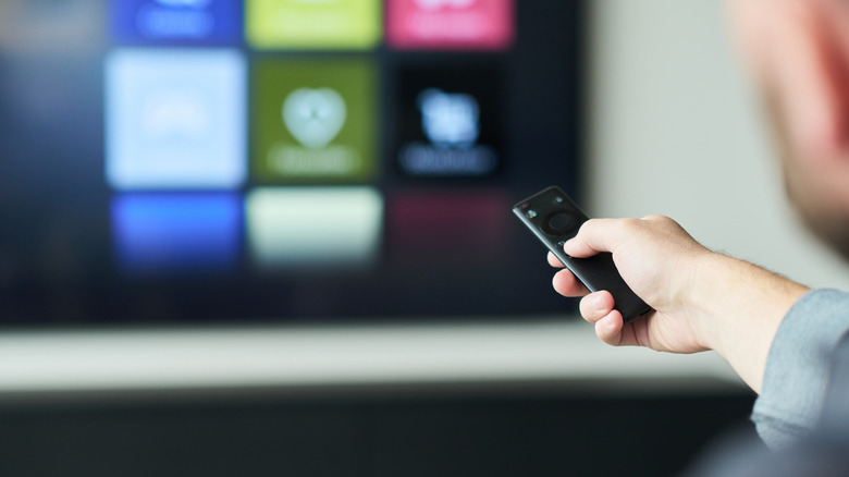 A closeup of a man holding remote to install apps on a smart tv