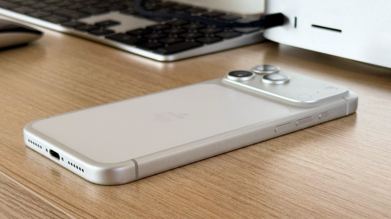 An iPhone 17 Pro Max on a desk with a Mac Studio and Studio Display behind it