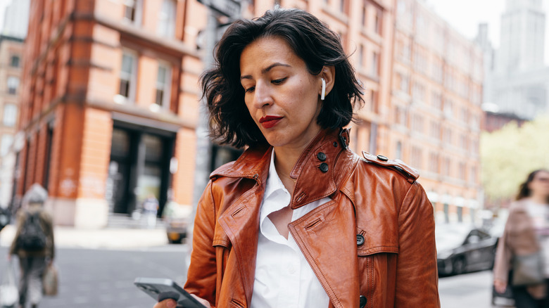 A woman with AirPods looking at her phone.