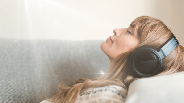 A woman lying on a couch with a pair of headphones on.