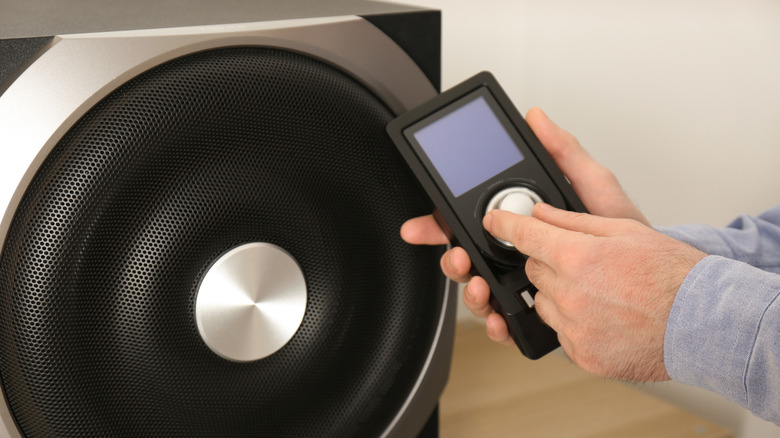 Close-up of a person using a remote to adjust a subwoofer