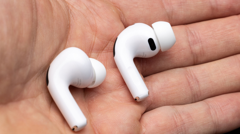 A person holding AirPods in their hand