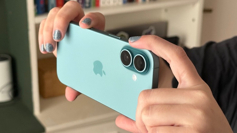 A woman holding an iPhone 16
