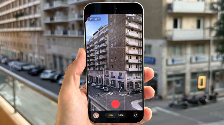 A hand holding an iPhone ready to record a video