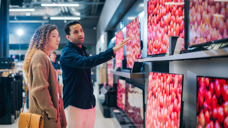 A couple looking at TVs in an electronics store