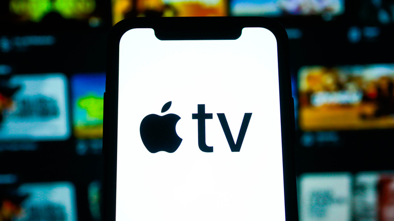 A phone showing the Apple TV logo with a TV with show icons in the background