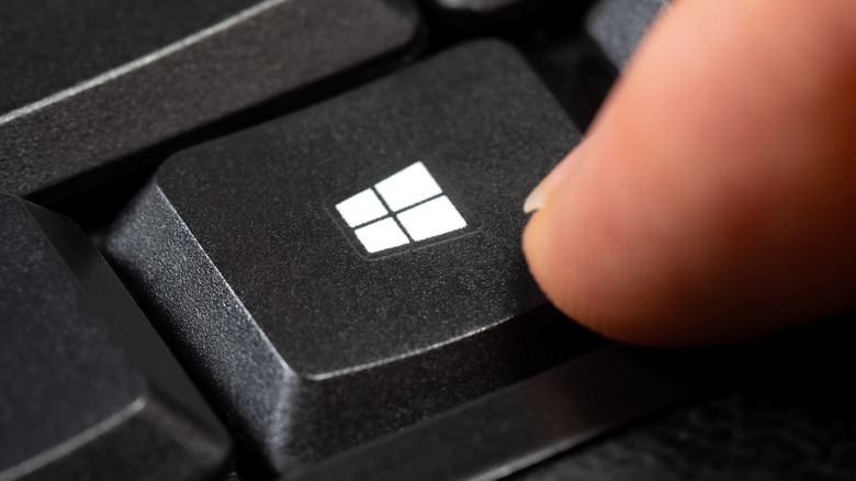 Finger pressing the dedicated Windows key on a keyboard.