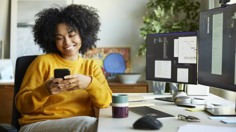 a woman sitting at a desk and using her Android phone