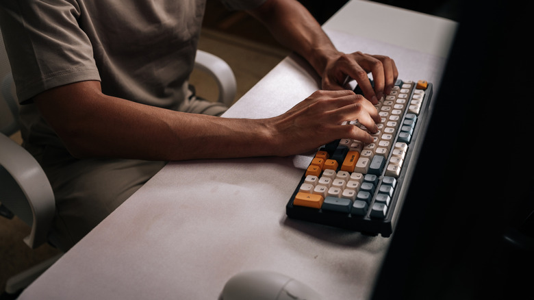 Overhead view of someone working on a multi-colored mechanical keyboard at a desk.