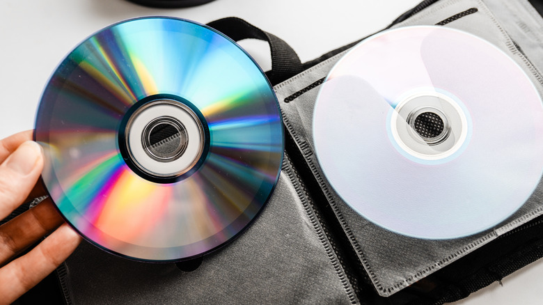 Person holding optical disc in front of a storage book