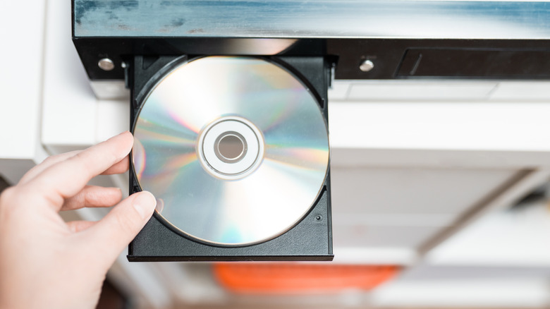 Hand inserting an optical disc into a player.