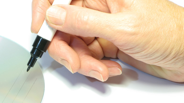 Person writing on a CD with a marker.