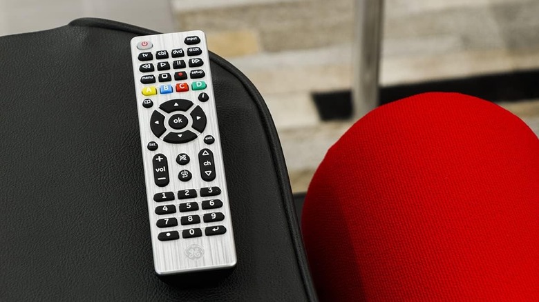 A GE universal remote resting on the arm of a couch.