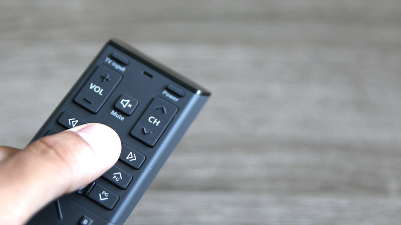 A close up of a person holding an Xfinity X1 remote.