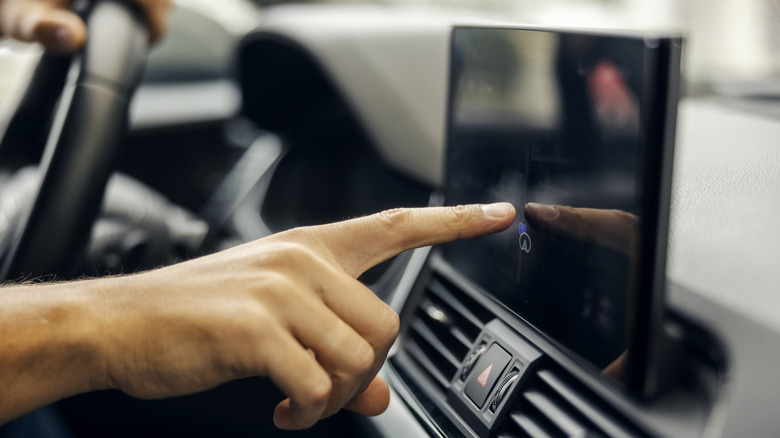 A person interacting with a vehicle infotainment screen.