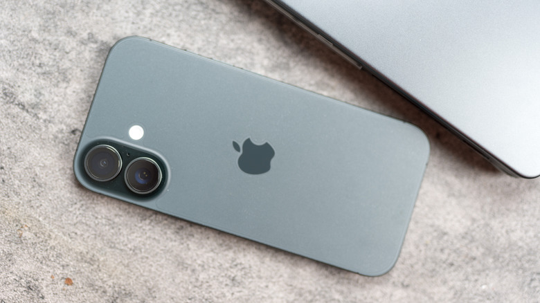 Apple iPhone 17 next to a laptop on a stone surface