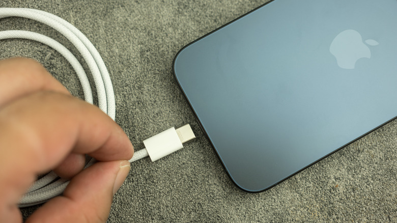 Close-up of a person connecting a charging cable to iPhone 15 Pro