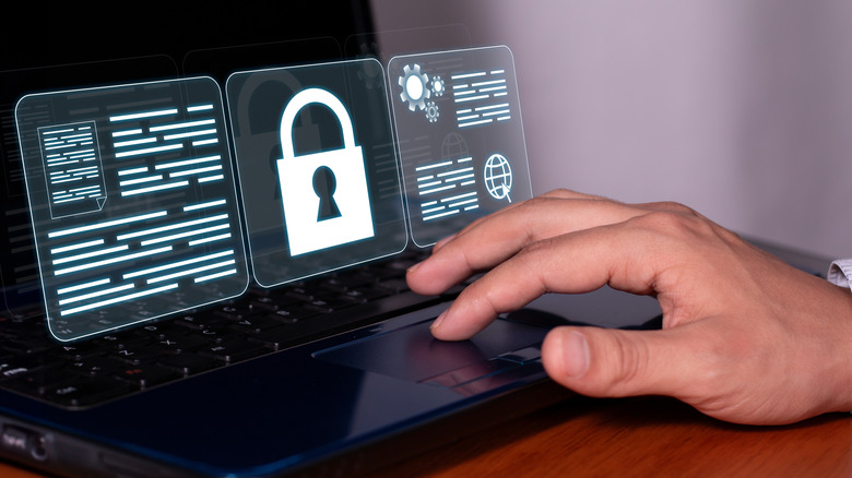 A person working on a laptop with a lock illustration in the foreground