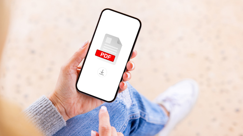A person holding a smartphone with PDF icon on the screen