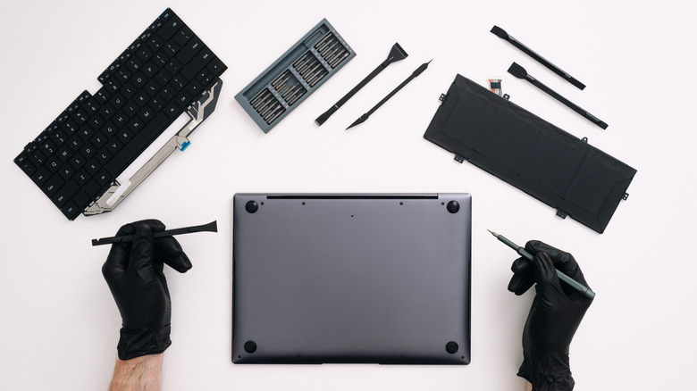A MacBook pro sitting upside down on a desk with components having been pulled out of it