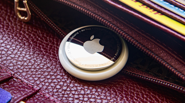 A closeup of an Apple AirTag inside a purple, leather purse