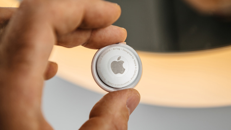 A closeup of an individual holding an Apple AirTag