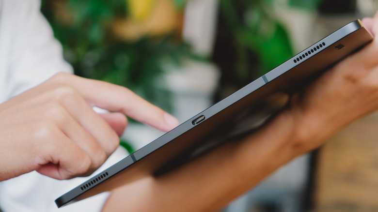 a person holding a Samsung Galaxy Tab S8 Ultra in their hands showing the side view of the USB-C