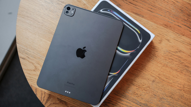 An M4 iPad sitting atop its box, with both items sitting on top of a wooden table