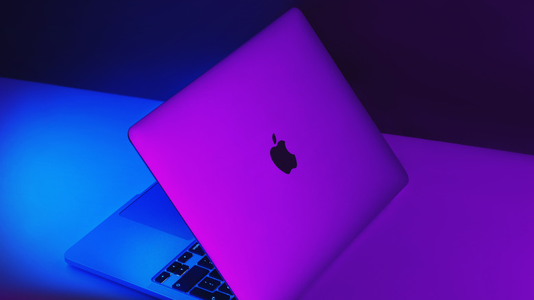 a MacBook on a table with blue and purple lighting