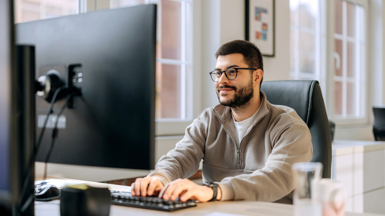 A man looking at his computer monitor while typing