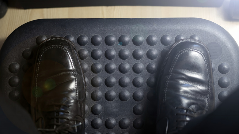A man's feet on a black footrest