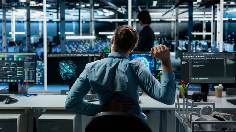 Woman at a desk holding lower back due to pain