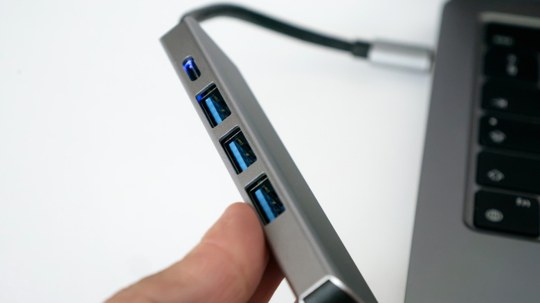Close up of a USB hub plugged into the side of a laptop.