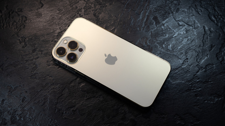 A silver iPhone 15 on a black, stone-like background