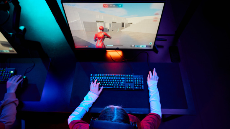 A gamer playing a third person shooter on a gaming laptop