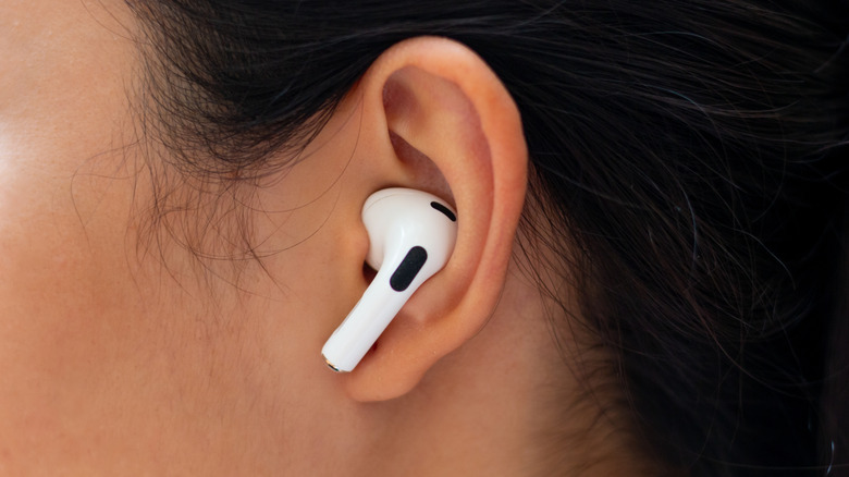 An AirPod resting in a person's ear.