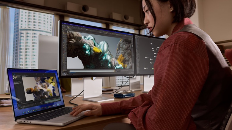 Woman using MacBook Pro on computer workstation
