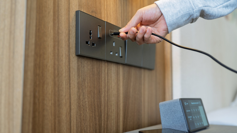 An image of someone plugging a USB-C cable into a wall-mounted USB port.