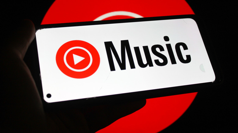 YouTube Music logo displayed on a smartphone screen with red hue in the background.