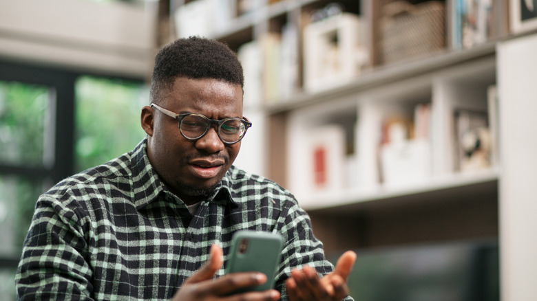 Man looking at phone frustrated.