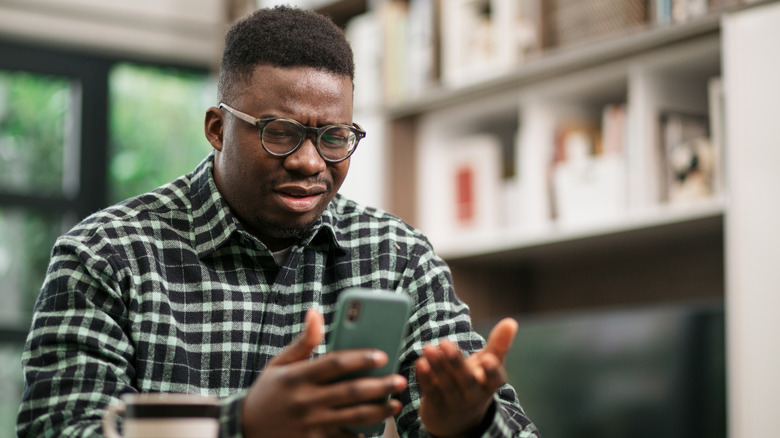 Man looking at phone frustrated.