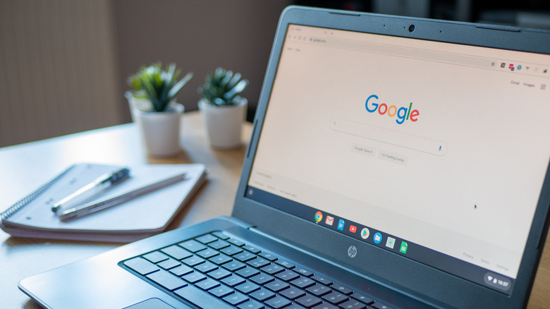 HP Chromebook opened on Google search page next to a paper notebook and pens