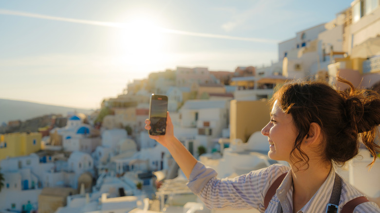 A woman taking a photo or video with a smartphone.
