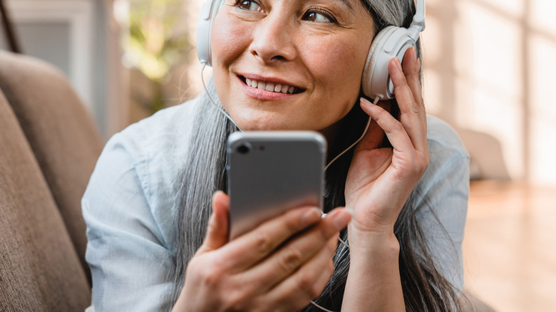 A woman listening to songs on an old phone with headphones on