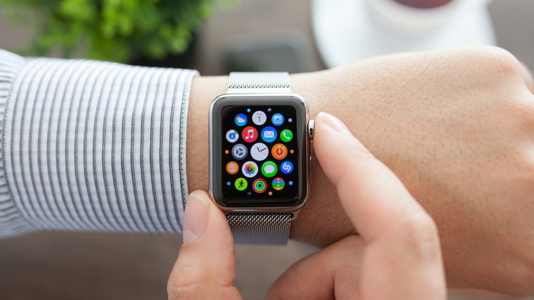 A wrist with an Apple Watch and a hand holding down the Digital Crown.