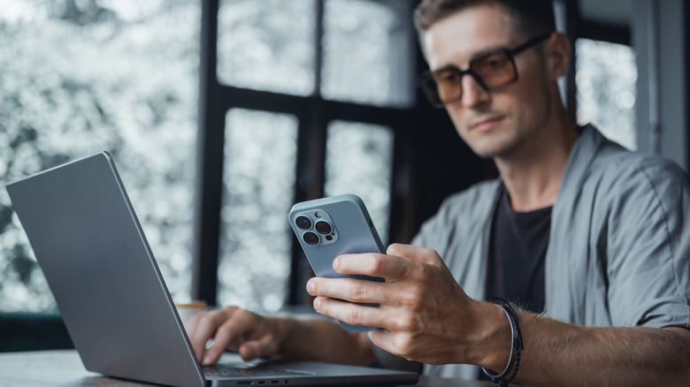 Man using iPhone and a laptop together