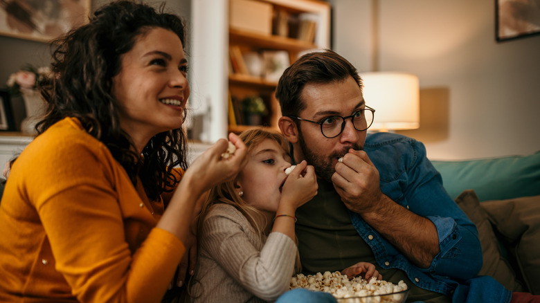 Family eating popcorn watching tv