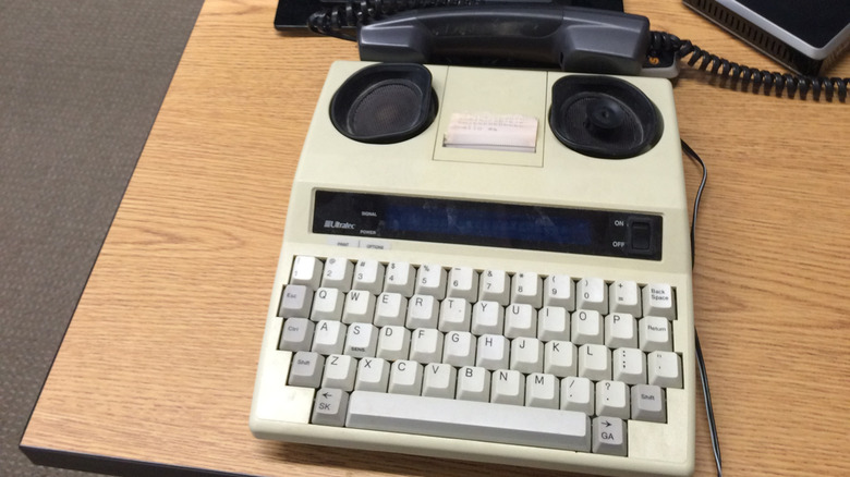 An old TTY machine on a desk connected to a landline