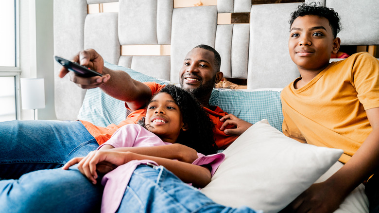 family watches TV while sitting together on the couch