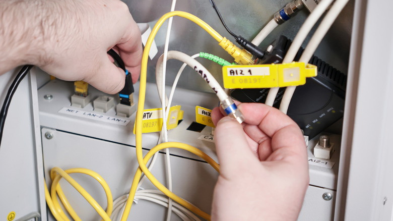 Technician connecting network and coaxial cables for maintenance.
